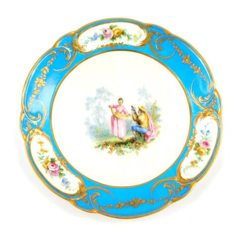 A Sevres style 19thC bleu celeste plate, painted centrally with a seated musician and a dancer in a woodland clearing, within a border of three reserve vignettes painted with flowers, gilt heightened, painted mark, 25cm diameter.