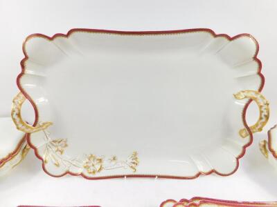 A Havilland Limoges porcelain part dinner service, moulded and gilt heightened with a floral sprig, within a red repeating flower head border, comprising six graduated twin handled platters, a pair of vegetable tureens and covers, a pair of sauce tureens - 2