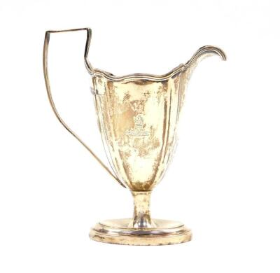 An Edward VII Adam style silver cream jug, of fluted and footed form, crest engraved, London 1904, 3.53oz.