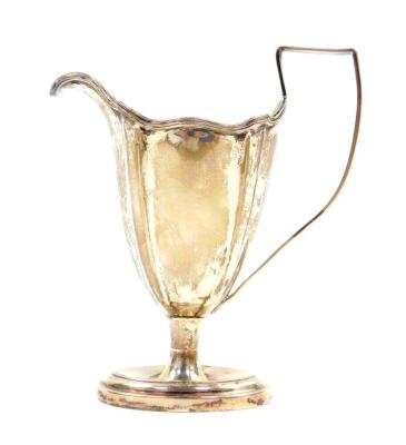 An Edward VII Adam style silver cream jug, of fluted and footed form, crest engraved, London 1904, 3.53oz. - 2