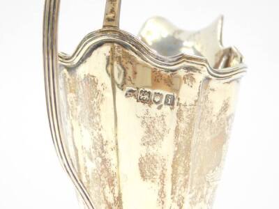 An Edward VII Adam style silver cream jug, of fluted and footed form, crest engraved, London 1904, 3.53oz. - 3