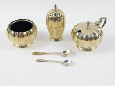 A silver three piece condiment set, of fluted gourd form, with blue glass liners, and spoons, Adie Bros, Birmingham 1964, 6.14oz.