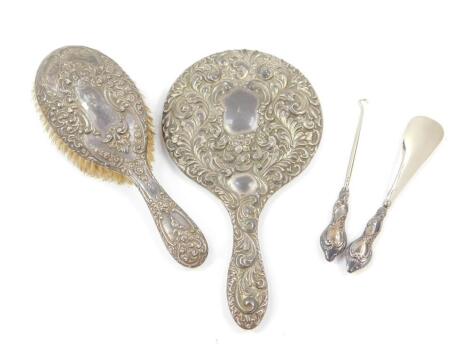 A George V silver handled button hook and shoe horn set, embossed with foliate scrolls, with shield reserves, cased, Chester 1913., Edward VII silver backed hair brush, embossed with flowers and rococo scrolls, Birmingham 1909, and a silver backed hand mi