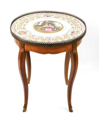 A late 19thC French occasional table, with a circular porcelain top, with gilt and floral garland border, enclosing a central fete galante scene of a young lady with her beau, and a lamb with spaniel in attendance, signed Garnier, enclosed with a gallerie