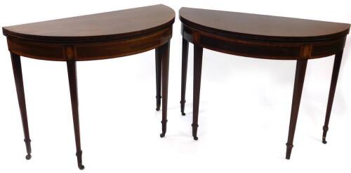 A pair of George III flame mahogany demi lune tables, one being a tea, the other a card table, with satin wood cross banded tops, and frieze with oval shell paterae, over square taper legs with line inlays and brass and ceramic castors, 100cm wide.