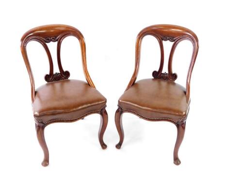 A pair of Victorian mahogany spoon back dining chairs, with studded leather seats, and cabriole legs.