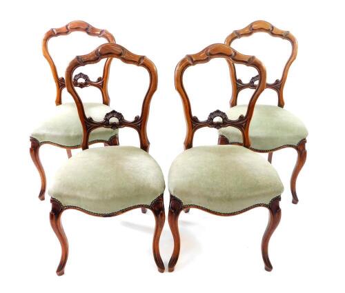 A set of four Victorian walnut carved balloon back dining chairs, with shell carved rails, studied seats and cabriole legs.