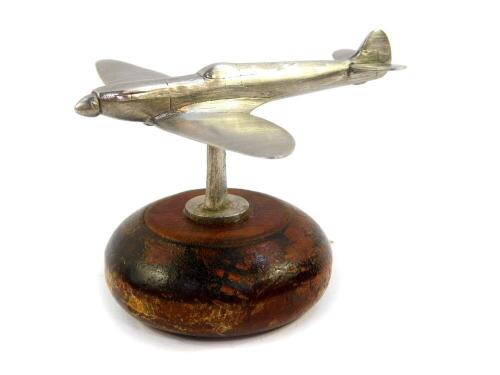 An aluminium paperweight modelled as a Spitfire, raised on a circular wooden base, 9cm wide.