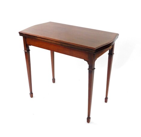 An Edwardian Sheraton Revival card table, with shaped rectangular fold over top with cross banding, on square taper legs with spade feet, 85cm wide.