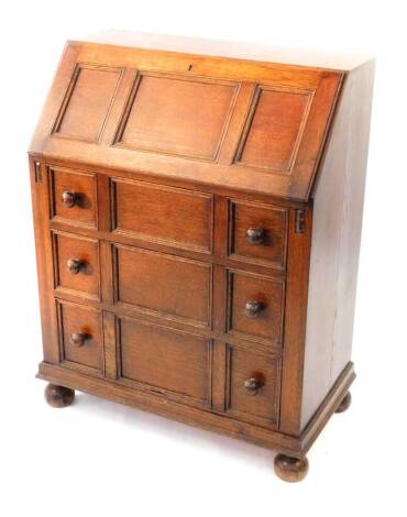 A mid 20thC oak bureau, with fall flap over three graduated drawers, with knob handles, 80cm wide.