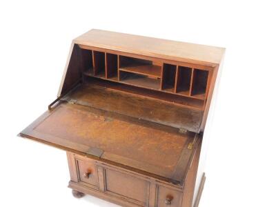 A mid 20thC oak bureau, with fall flap over three graduated drawers, with knob handles, 80cm wide. - 2