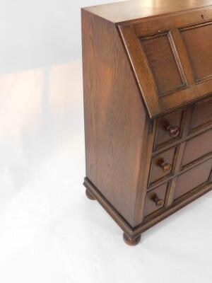 A mid 20thC oak bureau, with fall flap over three graduated drawers, with knob handles, 80cm wide. - 3