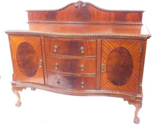 An early 20thC mahogany serpentine sideboard, with shaped splash back, gadrooned top, three central doors enclosed by concave doors, blind fret canted sides, and cabriole legs with ball and claw feet, 156cm wide.