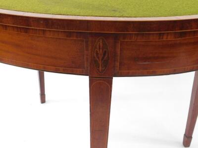 A George III mahogany demi lune card table, with satin wood cross banded folding top with baize insert, cross banded frieze with oval inlays over the square taper legs, 96cm diameter. - 4