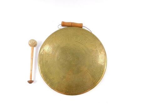 A Middle Eastern brass hand held dinner gong, with beater, 27cm diameter.