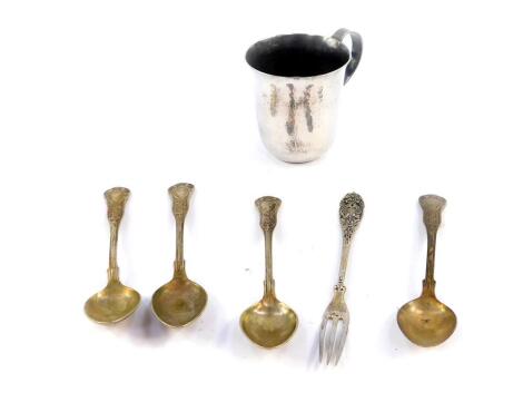 A Greek christening tankard, with hammered decoration, white metal, stamped 900, 3.57oz., together with four spoons and a fork, stamped 800, 4.23oz.