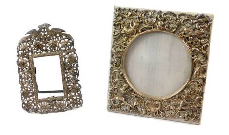 An Edwardian silver strut photograph frame, silk backed, embossed with cherubs and rococo scrolls, William Comyns, London 1905, 16.5cm high, 14.5cm wide., and a further strut metal frame, white metal, embossed with pheasants, flowers and foliate scrolls, 