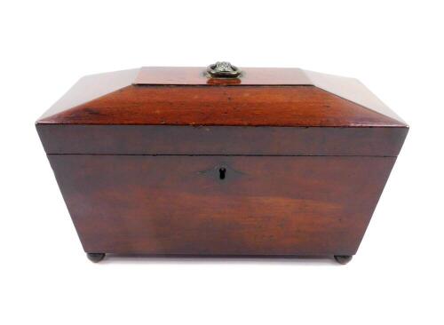 A Regency mahogany sarcophagus form tea caddy, opening to reveal two compartments, flanking a mixing bowl recess, raised on ball feet, 17cm high, 29cm wide, 15cm deep.