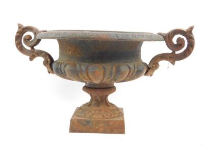 A 19thC cast iron urn, with leaf scroll handles, semi fluted raised on a square pedestal base, 24cm high, 46cm diameter.