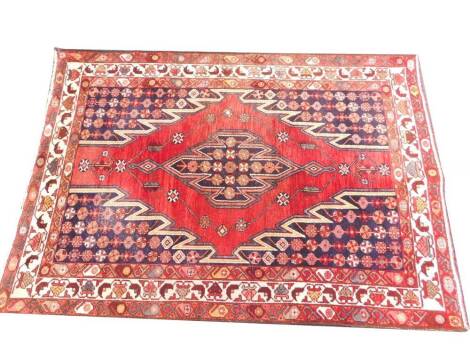 A Caucasian red ground rug, the central diamond motif decorated with guls, within a background of guls and borders of repeating botehs and floral motifs, 200cm x 138cm.