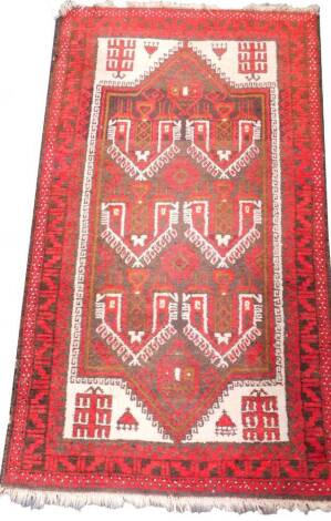 A Caucasian red ground prayer rug, decorated with six central geometric motifs and lanterns, within repeating geometric borders, 166cm x 89cm.