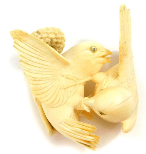 A Japanese ivory okimono, of a pair of sparrows squabbling over a head of millet, Meiji period, 11cm diameter, (AF).