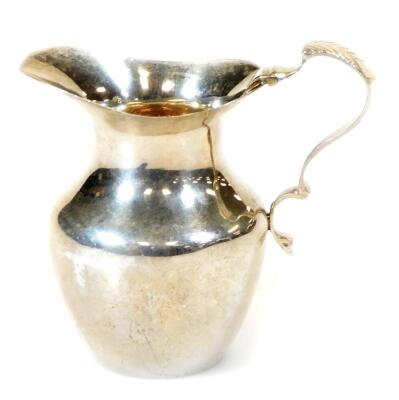 An Edwardian silver cream jug, with ear handle, silver gilt interior and shouldered body, Birmingham 1908, 9cm high, 2oz.