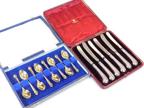 A set of eight Elizabeth II silver gilt teaspoons, by Pearce and Sons Limited, with shaped tricorn tops and plain bowls, Sheffield probably 1973, 10cm wide, 2.8oz, and a set of six silver handled pistol grip butter knives. (2 cases)