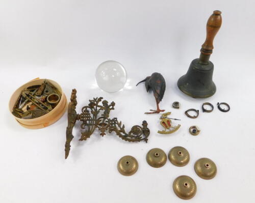 A brass bell with a turned wooden handle, 24cm high, a cold painted lead figure modelled as a stork, 15cm high, watch and music box fittings, glass ball magnifier, 9.5cm diameter, and a Victorian cast iron wall sconce, 22cm wide. (a quantity)