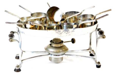 An early 20thC silver plated brandy pan warming set, comprising various pans with plain handles, on an oval stand with turned handles and removable burner beneath, the stand 29cm wide. (AF)