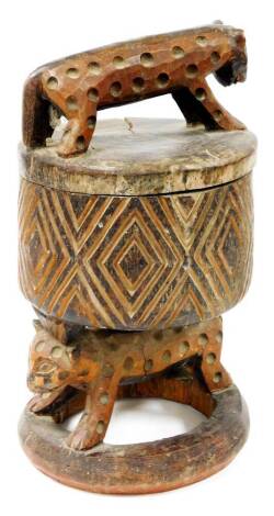 An African tribal headrest sculpture, with wild cat top, heavily carved cylindrical stem, resting on an animal's back, on a circular base, 46cm high.