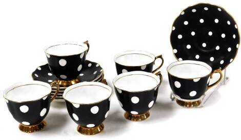 A Royal Albert six piece coffee set, comprising cups and saucers in a black and white spot pattern with gilt outline, each saucer 14cm wide.