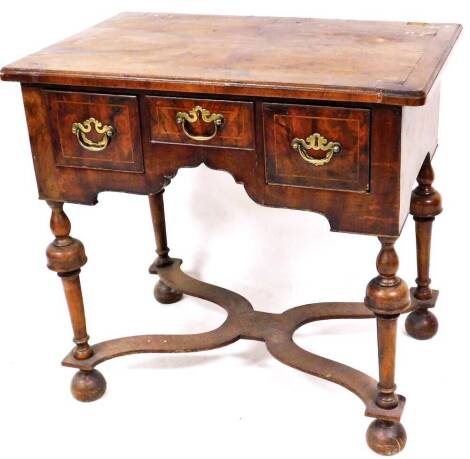 A late 18thC walnut lowboy, the rounded top raised above three frieze drawers, on turned legs, terminating in cupped bun feet, joined by an elaborate X stretcher, with an upper cross banding, 76cm high, 78cm wide, 51cm deep.