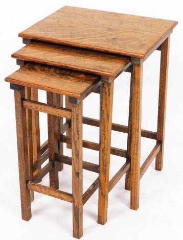 A set of three 20thC oak tables, each of rectangular form on block legs, joined by front to back stretchers, the largest 54cm high, 41cm wide, 30cm deep. (3)