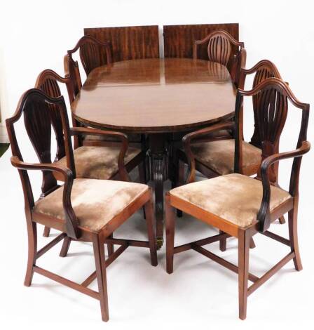 A Regency style mahogany twin pedestal dining table, with two leaves, set with a wide cross banding on a pair of twin pedestals each with reeded legs terminating in brass caps and castors, (when extended) 75cm high, 300cm wide, 104cm deep and a set of eig