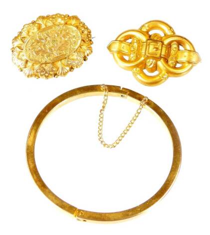 Various jewellery, a bangle of plain circular form 7cm diameter, a lozenge shaped belt buckle brooch, a further oval brooch, each unmarked. (3)