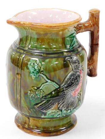 A late 19thC Majolica jug, with beak spout and bark handle, the main body raised with birds on a green ground on circular foot, unmarked, 26cm high.