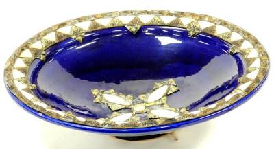 A highly decorative blue glaze pottery bowl, raised with mother of pearl finish and other metal mounts with a shaped centre and raised rim, unmarked, 42cm diameter.