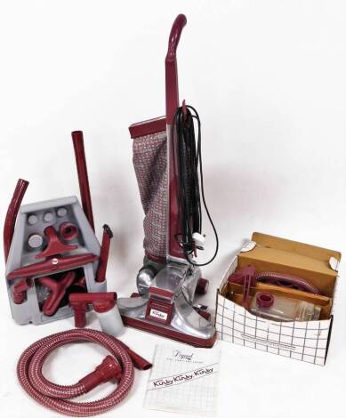 A vintage Legend Two Kirby vacuum cleaner, with chrome mounts in burgundy colours, 110cm high, with accessories.