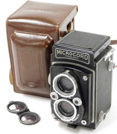 A 20thC Microcord box camera, in black textured pattern, 15cm high, with leather case.