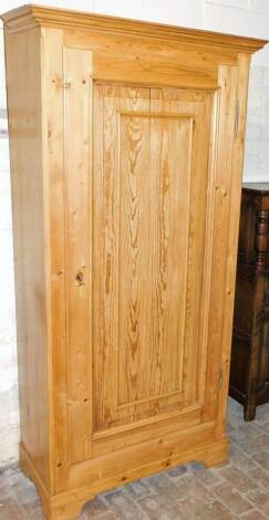 A reclaimed pine single wardrobe, with fixed moulded cornice, above a single panel door, on bracket feet, 205cm high, 100cm wide, 54cm deep.