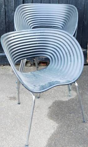 A set of four plastic patio style chairs, each of shaped oval form, with piercings to the centre, on chrome plated legs, terminating in compressed feet, 88cm high.