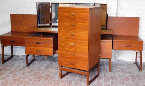 A EG G-Plan vintage teak matched bedroom suite, comprising a narrow chest of six long drawers, on shaped legs, joined by a front horizontal stretcher, 115cm high, 52cm wide, 46cm deep, a similar G Plan style dressing table and bed surround with leatherett