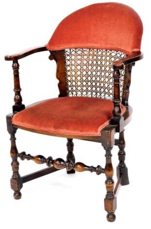 A mid 20thC oak stained armchair, with overstuffed back and bergere section above an overstuffed seat on baluster turned legs, joined by front to back stretchers, with carved scroll arms, 90cm high.