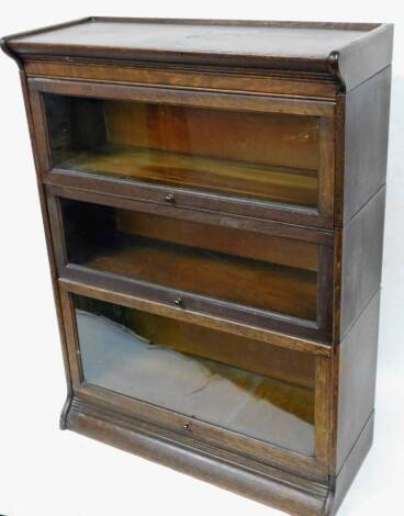 An early 20thC oak globe Wernicke style bookcase, in three sections on a moulded base with shaped cornice, 117cm high, 88cm wide, 36cm deep.