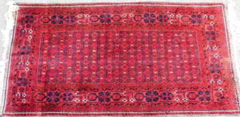 A 20thC Ingeles type rug, of rectangular form, the outer field decorated with flowers and scrolls, with an inner repeat geometric floral pattern, predominantly in red and blue, 210cm x 102cm.