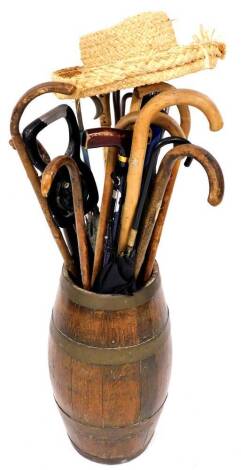 An early 20thC oak coopered stick barrel, of cylindrical form, with brass banding, 53cm high, containing a quantity of various walking sticks, shooting stick, straw hat, etc. (a quantity)