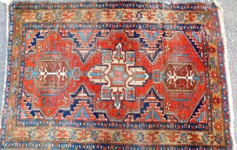 A 20thC Iranian rug of rectangular form, the centre decorated with three shaped floral sections, each predominately in orange, blue and cream, the outer field decorated with a geometric floral pattern in similar colours, 142cm x 96cm.