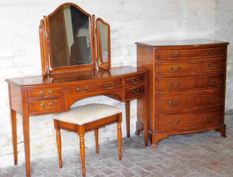 A late 20thC yew finish bow front chest, of five long graduated cock beaded drawers, on compressed stylised ball and claw feet, 104cm high, 87cm wide, 52cm deep, and a bow front dressing table with mirror.