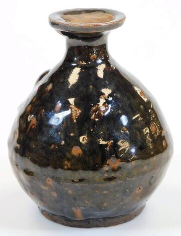 A West Country type glazed pottery bottle, of globular form, with a fixed seal to the neck, slip glazed overall with a brown splash decoration, 18cm high.